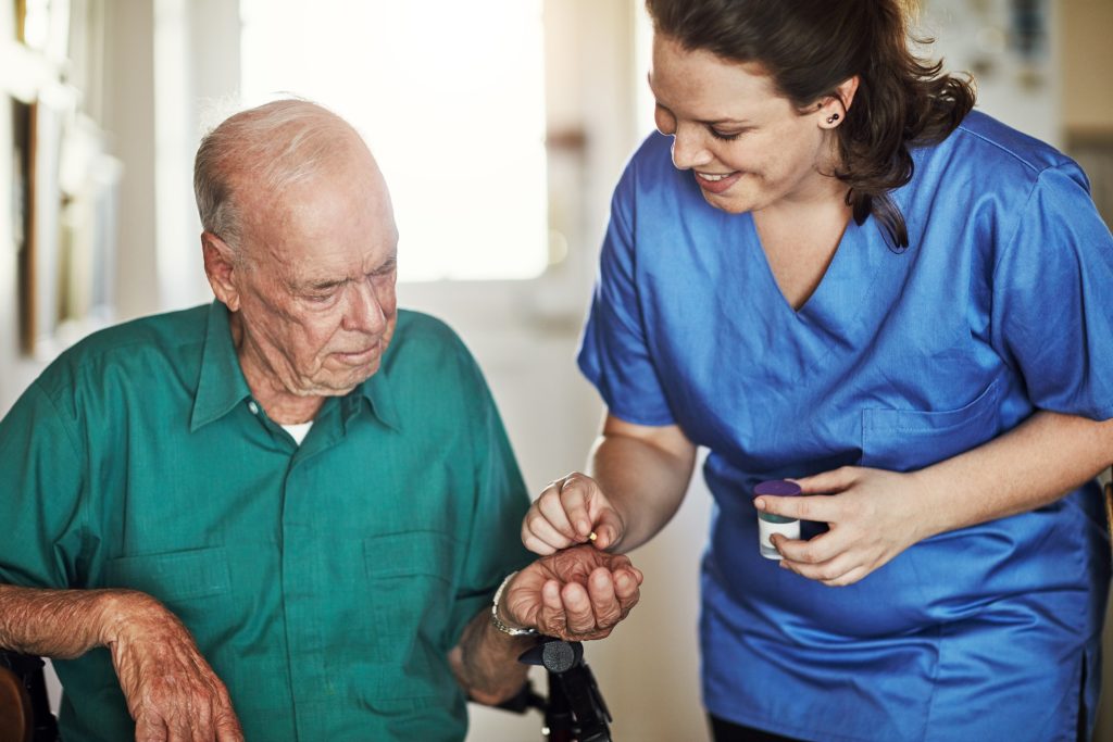Caregiver helping elderly man with his watch